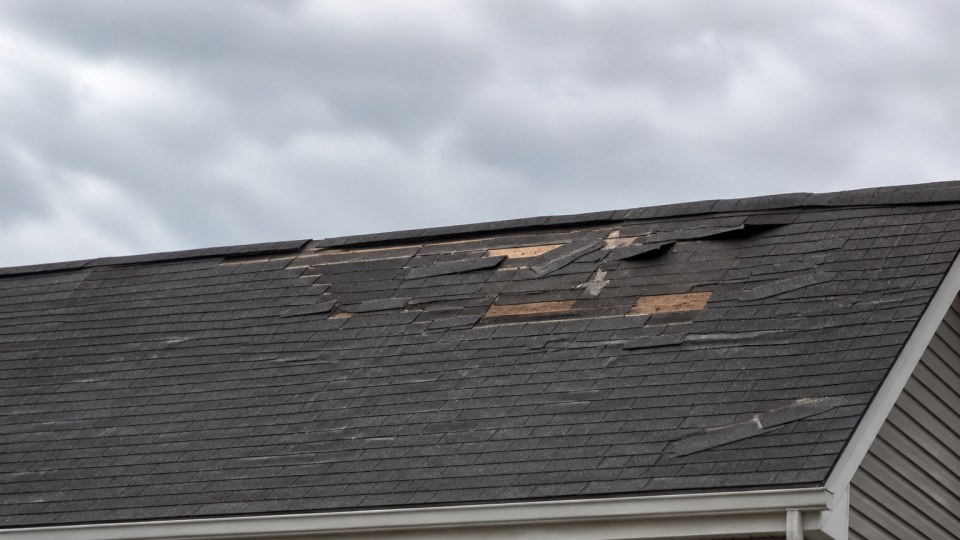 Storm damaged asphalt shingles on a Connecticut roof after a nor'easter